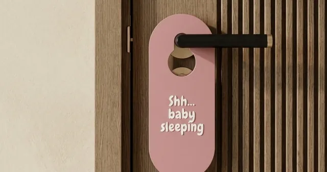 Pink door hanger reading Shh... baby sleeping on a lever handle.