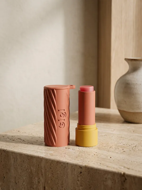 Terracotta fluted lip balm holder with a name up the side, next to a lip balm.