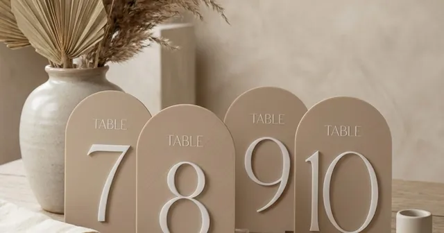 Beige arched table numbers 7 to 10 with TABLE captions, standing in their bases.